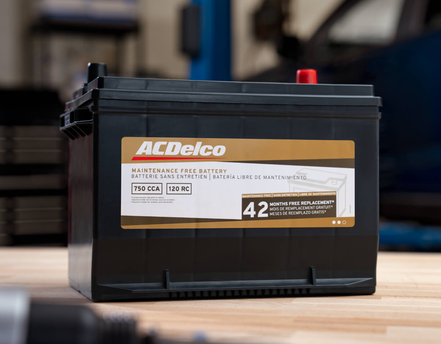 Close-up view of an ACDelco Maintenance Free Battery with 42 months replacement warranty resting on a workbench.