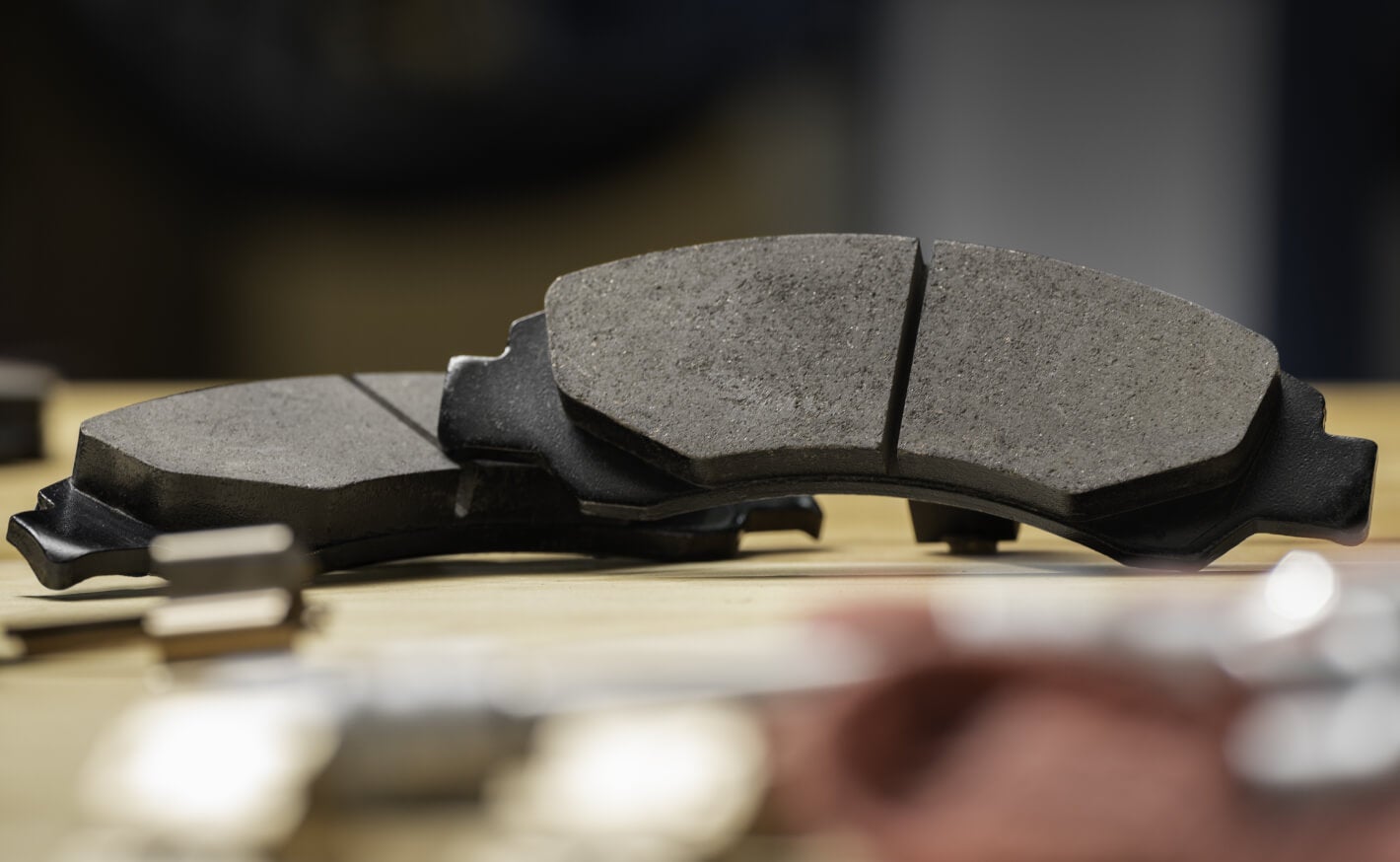 Close-up view of new OEM disc brake pads resting on a service bench in a shop.