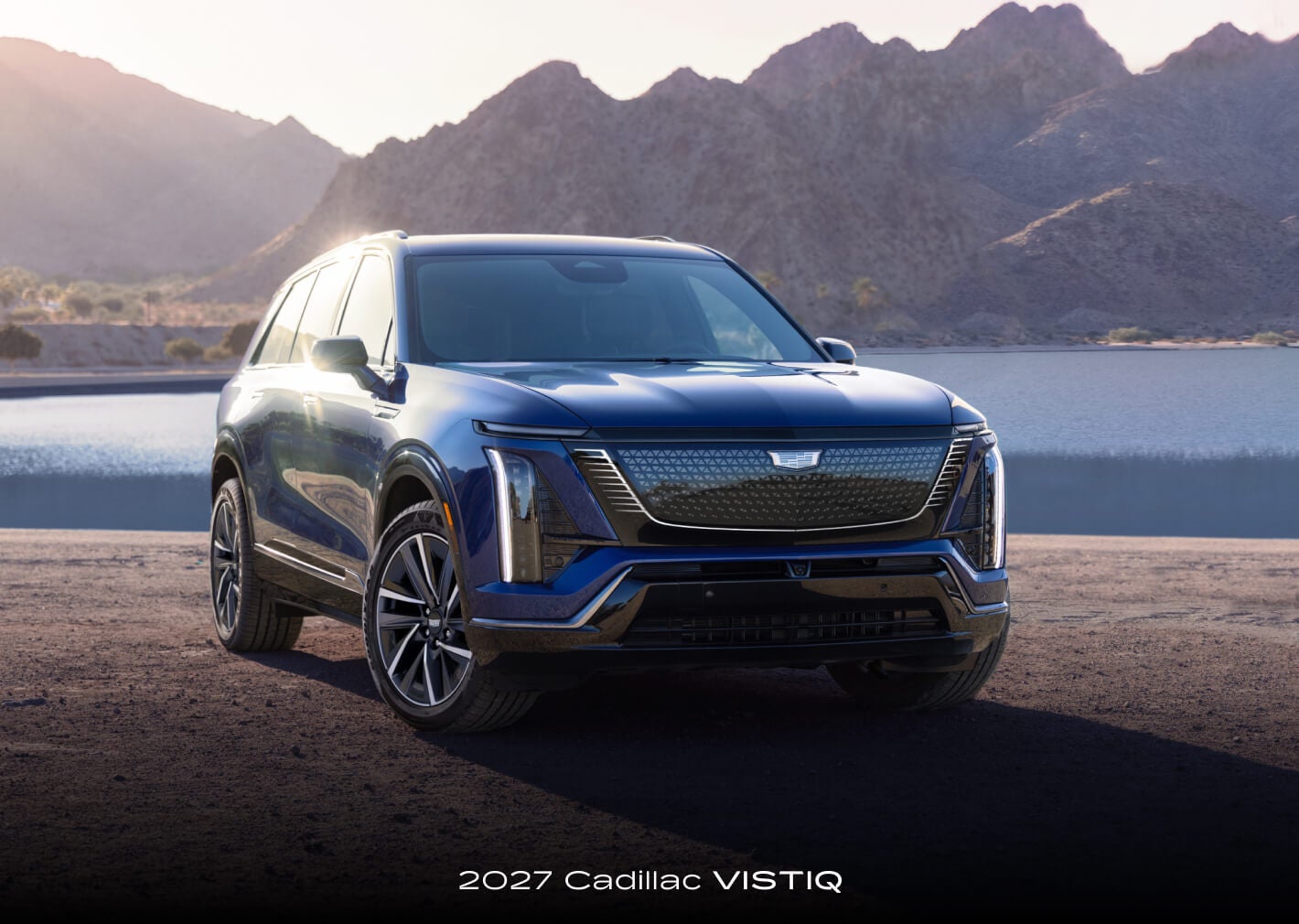 A front exterior view of a 2027 Cadillac VISTIQ parked by a remote mountain lake.