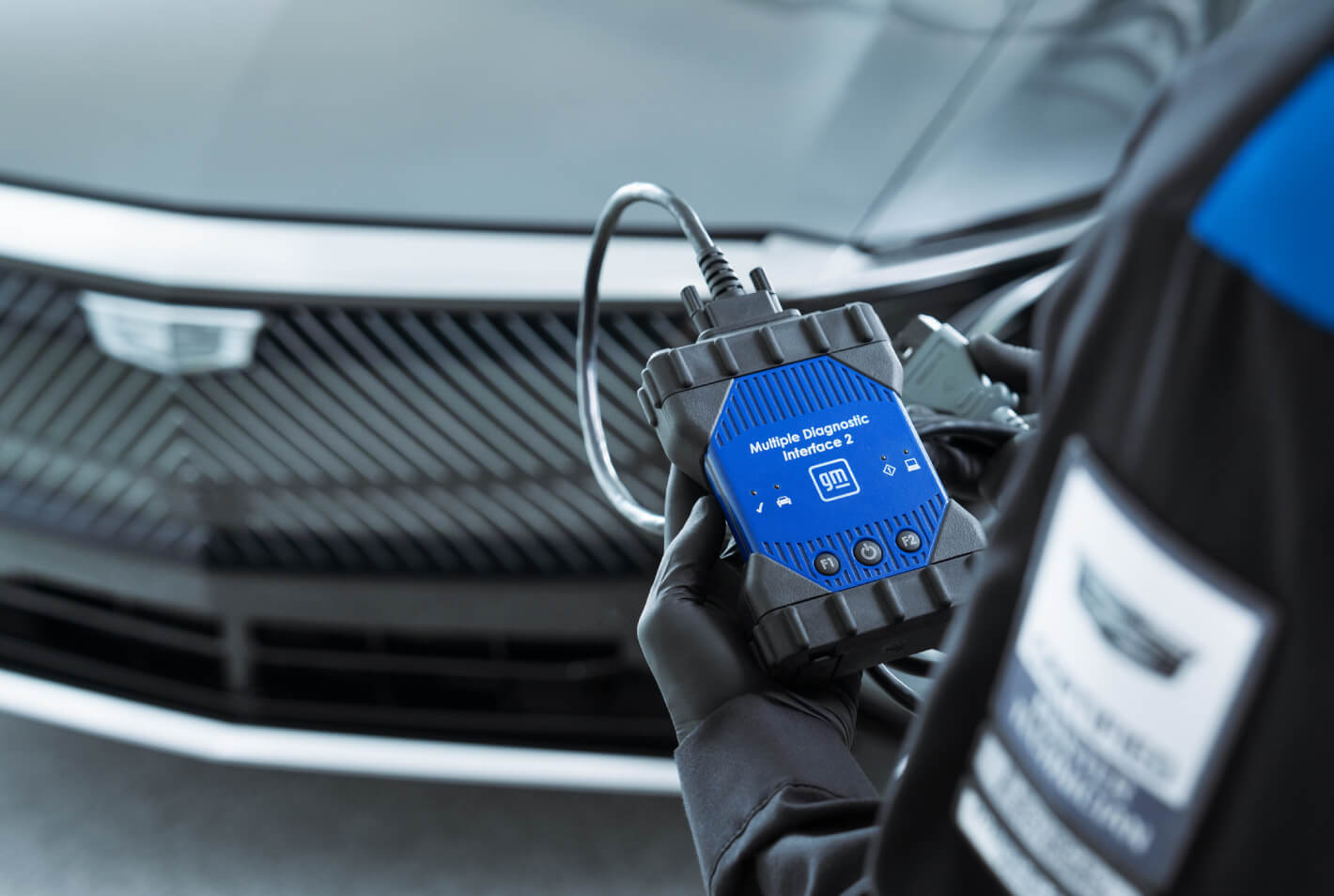  Close-up over the shoulder shot of a Cadillac Certified technician holding a diagnostic interface.