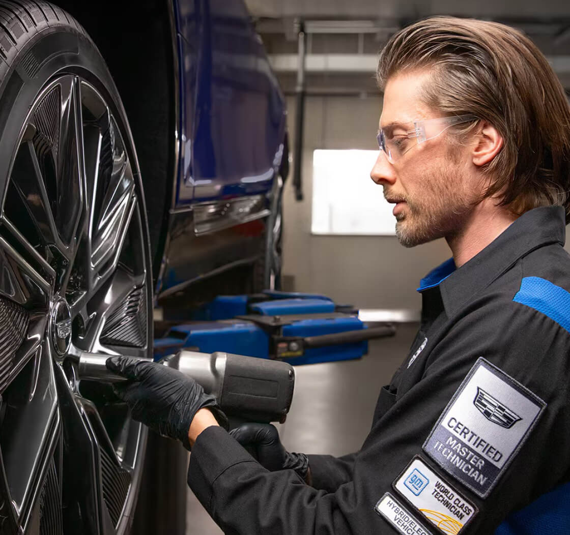 A Cadillac Service Technician uses a torque wrench on a Cadillac vehicle's wheel.